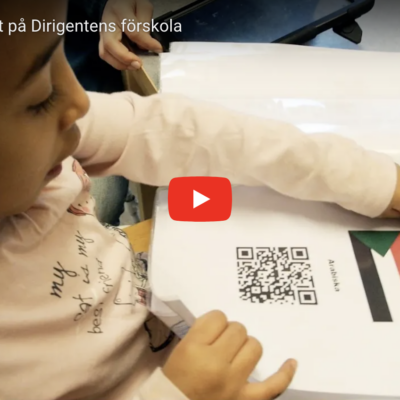 en flicka som pekar i ett häfte med QR-koder på sitt språks flagga