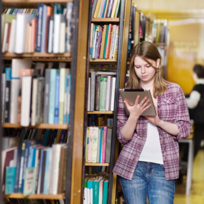 fokuserad elev tittar på sin ipad i biblioteket