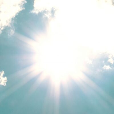 stark sol på blå himmel med tunna moln