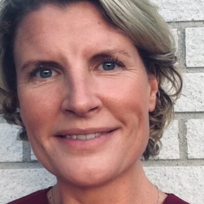 Forskaren Ebba Hildén i närbild framför en vit tegelvägg.