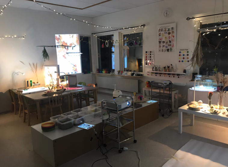 digital naturateljé på förskola. Flera bord med lampor, projektor, växter och burkar.