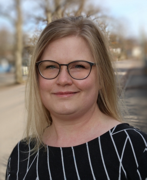 Sara Wahlberg med långt ljust hår, glasögon och svart tröja med vita ränder.