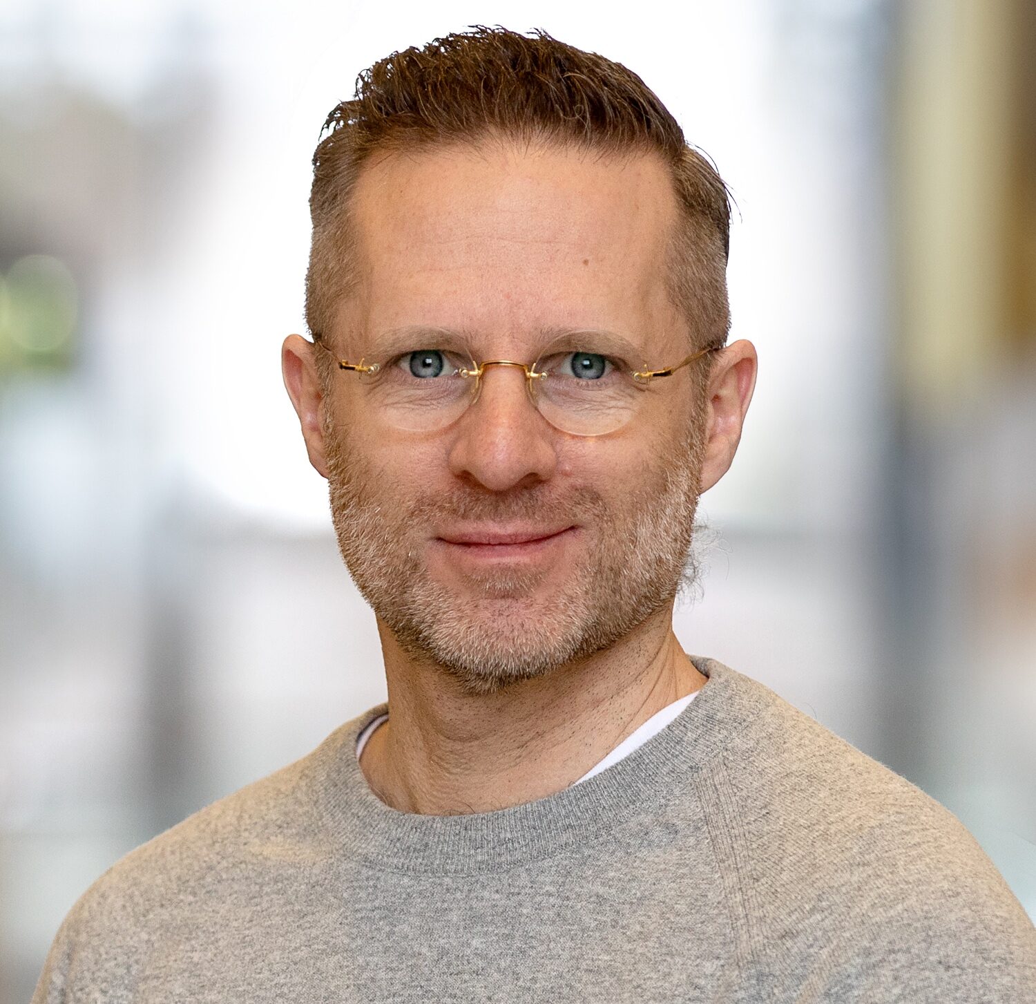Porträttbild man i grå tröja och glasögon.