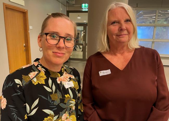 Två kvinnor med konferensnamnskylt på kläderna.